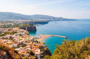 Yüksek uçurum manzarası, saf gök mavisi suyu, yüzen tekne ve gemileri, çakıl taşı plajları, Meta, Sant 'Agnello ve Napoli bölgesi yakınlarındaki Sorrento şehirlerinin kayalık çevresi.