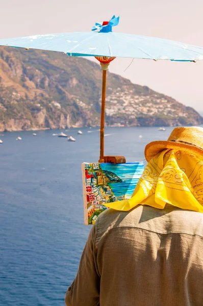 Художник малює пейзажі прекрасного узбережжя Позітано мальовничого скелястого краєвиду на скелі з блакитними морськими водами, повними яхт і високих гір. — стокове фото
