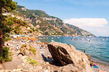 Sahilde uzanan büyük kayalar, insanların dinlenmesi, güneşlenmesi ve yüzmesi Positano 'daki Tyrhenian Denizi' nde inanılmaz ortaçağ şehrinde Campania, İtalya 'daki kayalık dağlarda