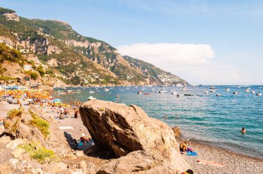 Sahilde uzanan büyük kayalar, insanların dinlenmesi, güneşlenmesi ve yüzmesi Positano 'daki Tyrhenian Denizi' nde inanılmaz ortaçağ şehrinde Campania, İtalya 'daki kayalık dağlarda