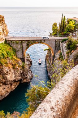 Campania bölgesindeki Tyrhenian körfezi üzerindeki yüksek kayalık uçurumlar arasında inşa edilen Fiordo di Furore ark köprüsünün görüntüsü. Köprüde giden bir araba, altında yüzen eşsiz bir körfez.