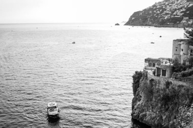 Campania 'daki Fiordo di Furore ve Positano Dağları yakınlarındaki Tyrrhenian deniz koyunun siyah ve beyaz manzarası. Suda yüzen tekneler, uçurumlarda açık terasları olan özel evler.
