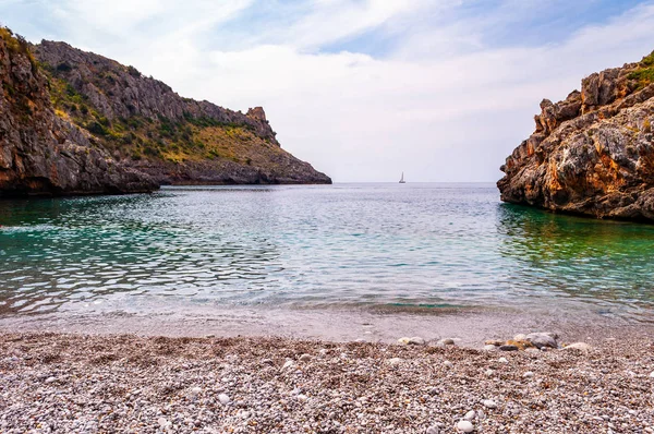 Increíble playa de Cala Bianca rodeada de rocas y bahía del mar Tirreno con aguas cristalinas y profundas llenas de vida submarina. Yate de mar flotando en la playa de Cala Bianca en la región de Campania en Italia — Foto de Stock