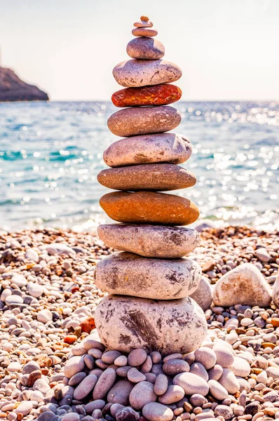 Вежа з плоских каменів на пляжі. Балансування каменю - це художня дисципліна, або хобі, в якій камені природно зрівноважуються один над одним в різних положеннях. Кала Б "янка Італія — стокове фото