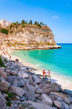 Dinlenmiş güneş banyosu ve yüzen insanlarla dolu ünlü Rotonda Sahili manzarası. Santa Maria Tapınağı Büyük bir uçurumun zirvesinde
