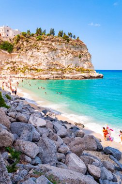 Dinlenmiş güneş banyosu ve yüzen insanlarla dolu ünlü Rotonda Sahili manzarası. Santa Maria Tapınağı Büyük bir uçurumun zirvesinde