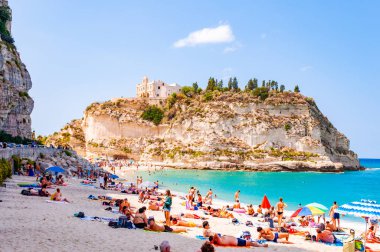 Dinlenmiş güneş banyosu ve yüzen insanlarla dolu ünlü Rotonda Sahili manzarası. Santa Maria Tapınağı Büyük bir uçurumun zirvesinde