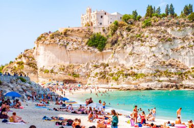 Dinlenmiş güneş banyosu ve yüzen insanlarla dolu ünlü Rotonda Sahili manzarası. Santa Maria Tapınağı Büyük bir uçurumun zirvesinde