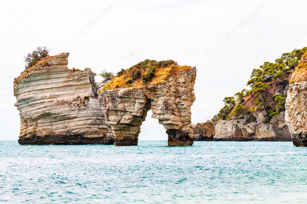 Famous sea stacks of Baia delle Zagare bay in Gargano National park. Natural rock sculptures made by Adriatic sea waves, wind and erosion stacked in the sea near the rocky beach