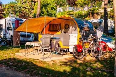 Sabah gölgeli teraslı modern sarı karavan Garda Gölü 'nün güney kıyısındaki La Ca kampında.