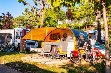 Sabah gölgeli teraslı modern sarı karavan Garda Gölü 'nün güney kıyısındaki La Ca kampında.