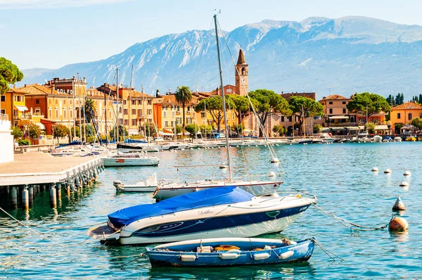 Widok na jachty żaglowe i łodzie zaparkowane na krystalicznie czystej, błękitnej wodzie niesamowitego jeziora Garda i Toscolano Maderno krajobraz miasta na tle — Zdjęcie stockowe