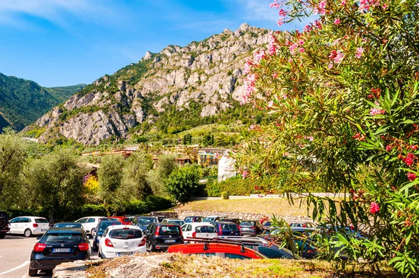 Jedno z mála parkovacích míst ve městě kvetoucí rostliny a olivovníky rostoucí v okolí soukromých domů, hotelů a dolomitových hor na pozadí — Stock fotografie