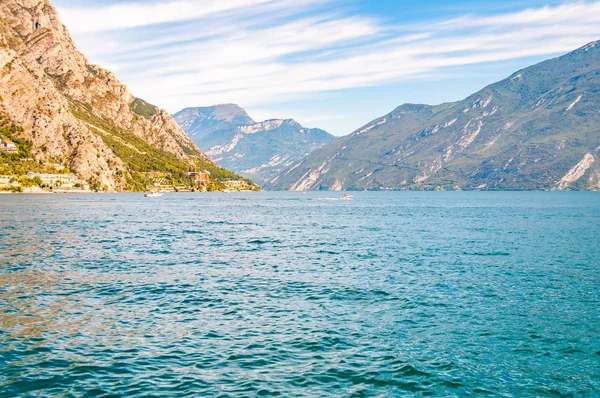 Fantastisk Gardasjö i Lombardiet, Italien omgiven av höga dolomitberg. Båtar och yacht flyter på sjön. Olika hotell och privata hus byggda på den steniga stranden av sjön — Stockfoto