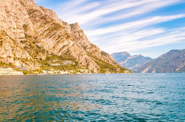 Fantastisk Gardasjö i Lombardiet, Italien omgiven av höga dolomitberg. Båtar och yacht flyter på sjön. Olika hotell och privata hus byggda på den steniga stranden av sjön — Stockfoto