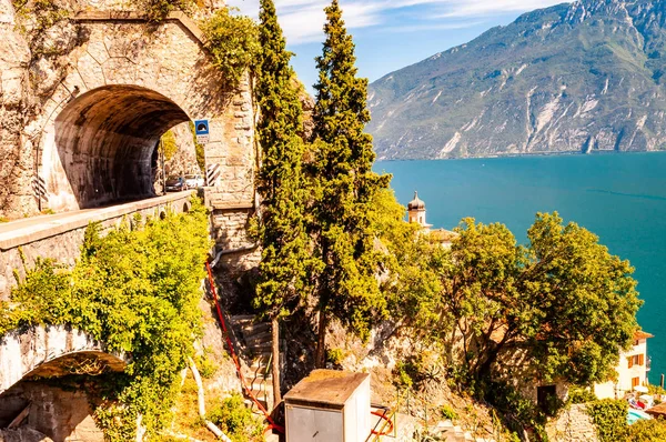 Escénica carretera panorámica alrededor del lago de Garda llena de túneles y galerías hechas en las rocas en el borde de una costa. Carreteras italianas y naturaleza Imagen De Stock