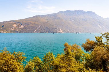 Dolomite dağları ve hareketli kuzey İtalya doğası ile çevrili Garda Gölü 'nde rüzgarla hızlı giden siyah yelkenliler.