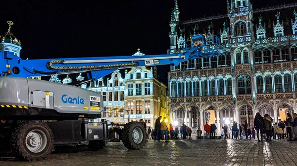 Nattfotografering av teleskopisk bom hiss maskin stående på Grand Place eller Square eller Grote Markt eller Grand Market som är det centrala torget i Bryssel. Stockbild