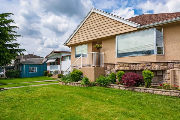 Modest family house with green lawn in front. Old residential house