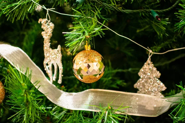 Gouden kerstbal tussen de kerstboom brenches. Close-up look van de bal. — Stockfoto