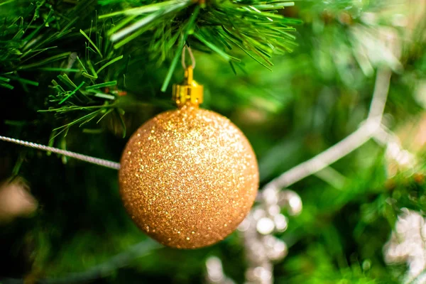 Gyllene grannlåt bland julgransbrynen. Närbild utseende av bollen. — Stockfoto