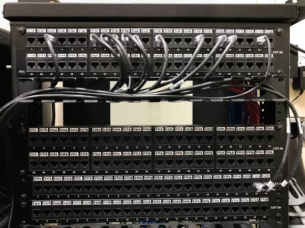 Ethernet patch panels in communication room with cables connected to the ports