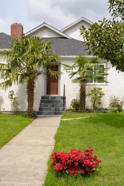 Paved pathway to the house entrance over front yard decorated with red flowers — Stock Photo, Image