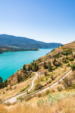 Su ve dağ sırtı manzaralı göl kıyısında büyük lüks evler.