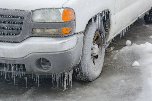 Icicles of freezing rain covering head light, bumper, and wheel of the truck — Stock fotografie