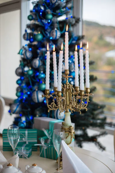 Свеча с зажженными свечами у елки с подарками — стоковое фото