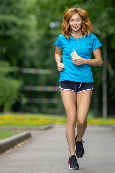 Joven asiático mujer con rojo cabello jogging en un ciudad parque —  Fotos de Stock