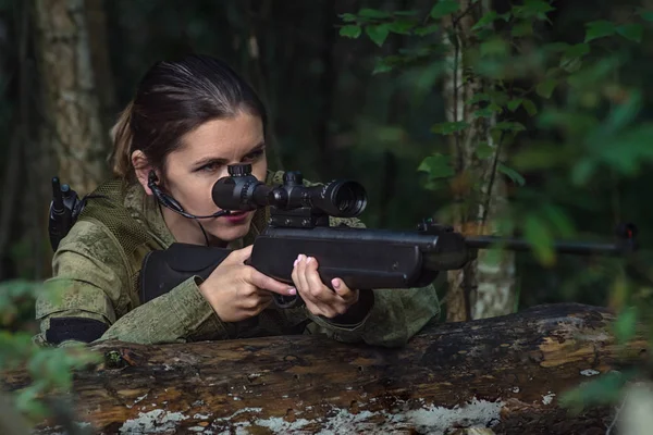 Güzel asker kız portresi, silahlı asker kadın optik görüşlü ve ormanda askeri üniformalı.