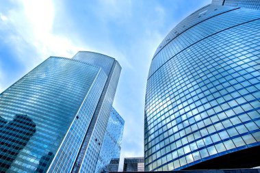 Low angle view of tops of modern new business corporate buildings against the blue sky.