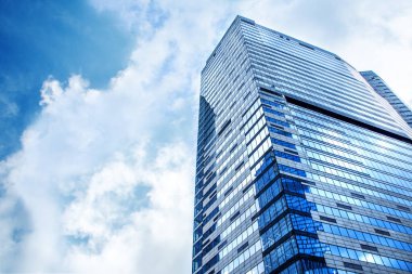 Low angle view of tops of modern new business corporate buildings against the blue sky.