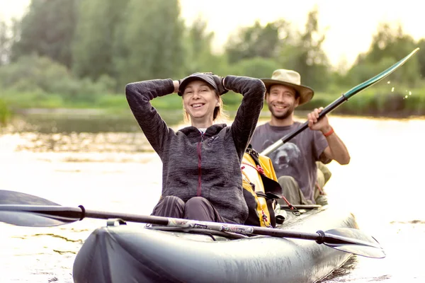 Gyönyörű fiatal pár együtt kajakoznak a folyón és mosolyognak a nyári napon. — Stock Fotó