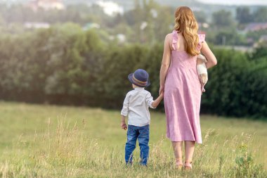 Arka plan portresi mutlu aileyi parkta çimlerin üzerinde kucaklıyor. Anne ve çocuğu ve küçük köpekleri. Aile kavramı