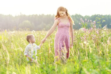Güzel, mutlu bir anne ve kızın portresi. El ele tutuşup, yeşil bir çayırda birlikte gülümsüyorlar. Mutlu aile kavramı