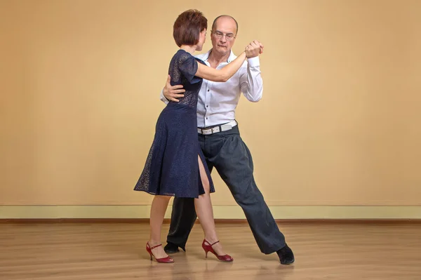 Erkek ve kadının tam boy portresi el ele tutuşarak tango yapıyor. Şehvetli dans konsepti
