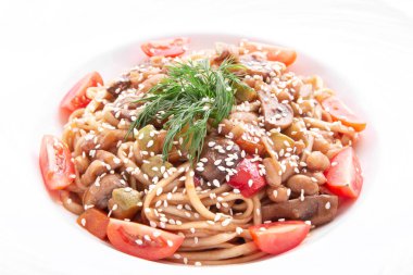 Kiraz domatesli İtalyan makarnası, mantar, susam ve dereotu yuvarlak tabakta. Yukarıdan bak. beyaz üzerine izole