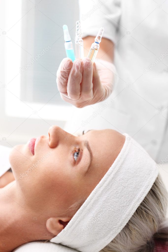 Vitamin cocktail in an ampoule, a woman in the beauty salon.Cosmetic ampoule, serum applied to the face of a woman.
