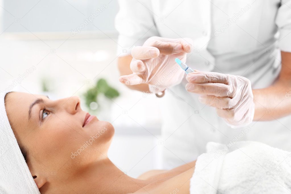 Cosmetic ampoule, serum applied to the face of a woman.