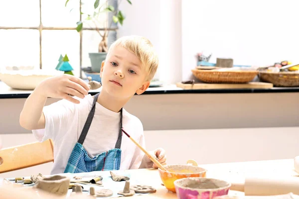 Le garçon griffe de l'argile dans un atelier de plastique. . — Photo