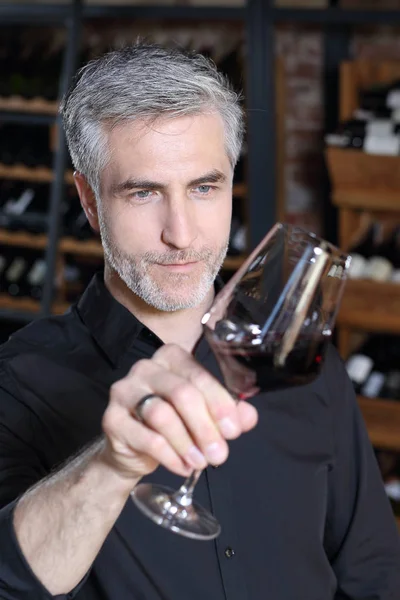 Een knappe man rechters de kleur van rode wijn. — Stockfoto