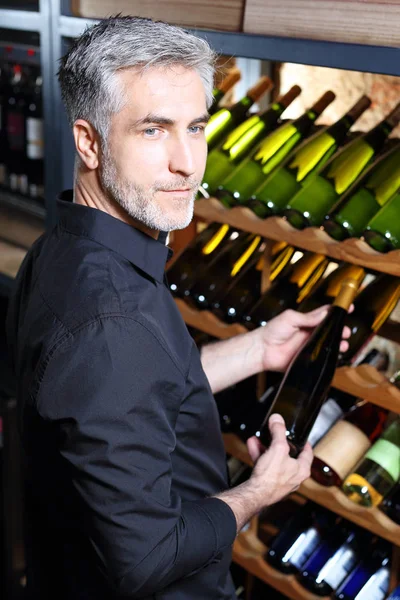 ワインセラー。ワイン コレクションです。男は老化のワインを選択します。 — ストック写真