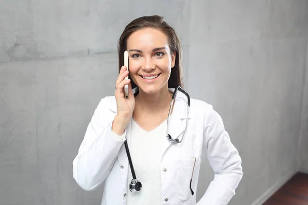 電話で医者 白いオーバー オールに身を包んだ医師診療所の略で 携帯電話で話しています — ストック写真