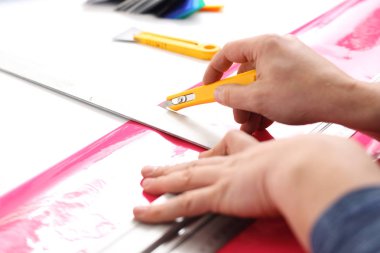 Dijital baskı folyo üzerinde. Çalışanın folyo bir bıçakla keser.