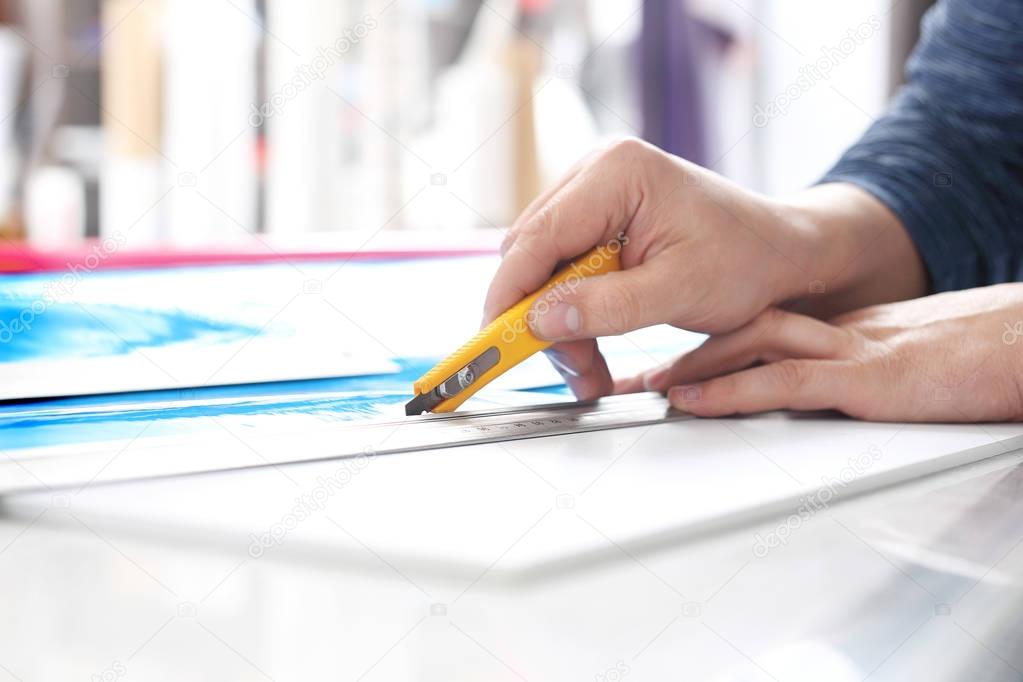 Cutting paper with a knife. The employee cuts the foil with a knife