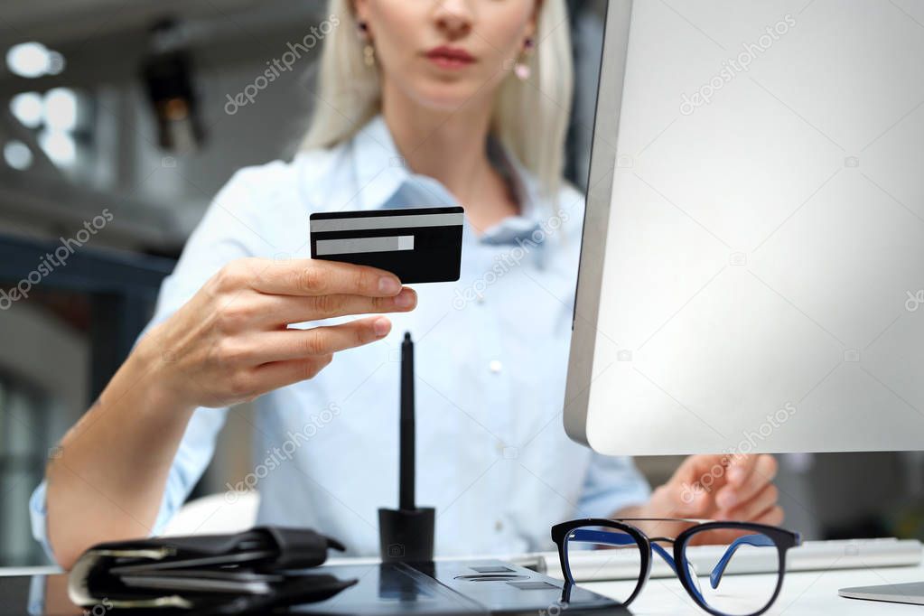 Online shopping. A woman uses a credit card to pay in the computer.