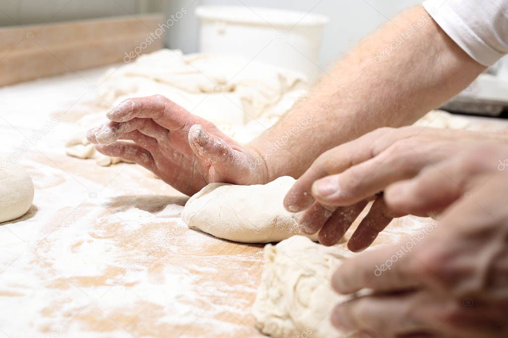 Pizza dough. The man kneads the dough.