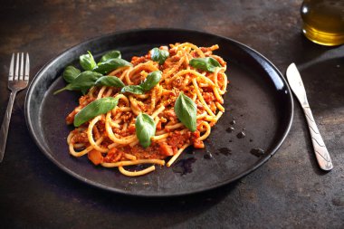 İtalyan yemeği. Spagetti makarna siyah bir tabakta domates ile